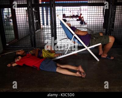 MARIKINA CITY, Philippinen - 28. AUGUST 2017: ein Mann und eine junge Schlafen auf dem Gehsteig außerhalb ein Sportstadion in Marikina City, Philippinen Stockfoto
