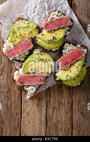 Super Essen: Sandwiches mit Thunfisch Steak in Sesam, Avocado und Hüttenkäse close-up auf den Tisch. Draufsicht von oben vertikal Stockfoto