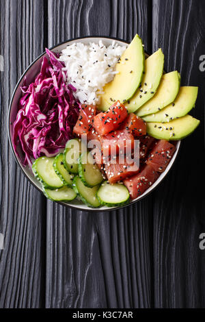 Raw Organic Ahi-thunfisch Poke Schüssel mit Reis und Gemüse close-up auf den Tisch. Draufsicht von oben vertikal Stockfoto
