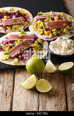 Appetitliches Essen: Tacos mit Thunfisch, Sesam, Mais, Rotkohl und Avocado close-up auf dem Tisch. Vertikale Stockfoto