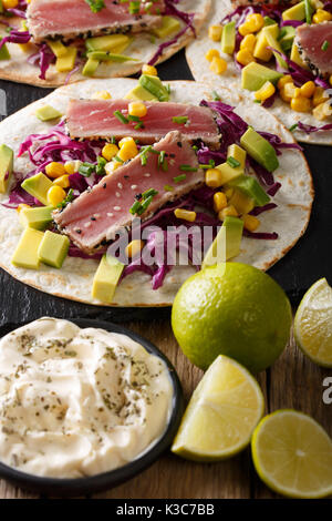 Leckeres Essen: Fisch Tortillas mit Thunfisch, Sesam, Mais, Kohl und Avocado close-up auf dem Tisch. Vertikale Stockfoto