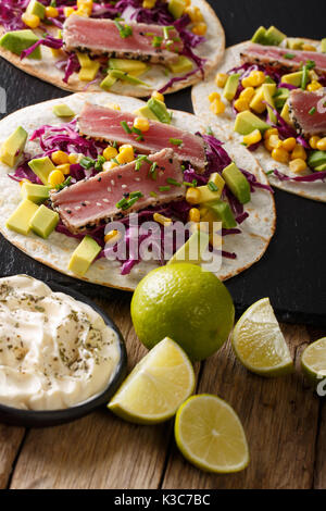 Tortilla mit Thunfisch, Sesam, Mais, Kohl und Avocado close-up auf dem Tisch. Vertikale Stockfoto