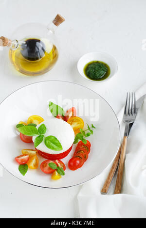 Caprese Salat mit reifen Tomaten und Mozzarella mit frischem Basilikum Blätter auf weißem Hintergrund. Ansicht von oben. Stockfoto