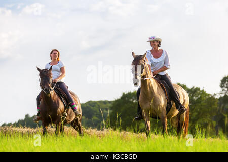 Zwei Frauen fahrt Andalusische Pferde in die Felder Stockfoto