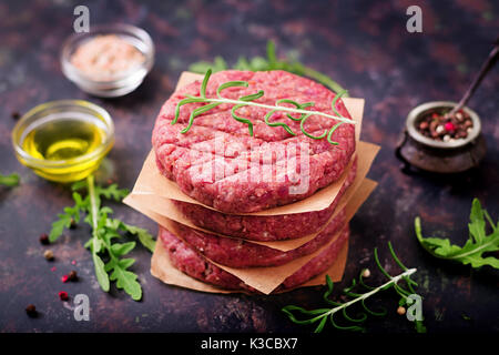 Frische rohe hausgemachte Hackfleisch Steak Burger mit Gewürzen auf schwarzem Hintergrund Stockfoto