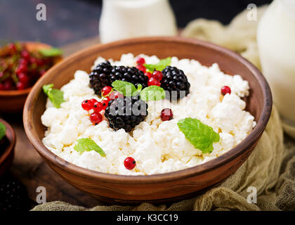Hüttenkäse mit Brombeeren in eine Schüssel geben. Stockfoto