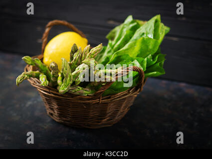 Frischer Spargel im Warenkorb auf dunklem Hintergrund. Stockfoto