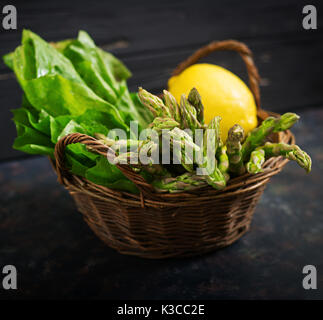 Frischer Spargel im Warenkorb auf dunklem Hintergrund. Stockfoto