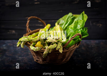 Frischer Spargel im Warenkorb auf dunklem Hintergrund. Stockfoto