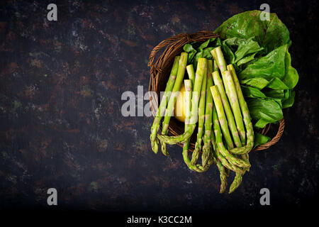 Frischer Spargel im Warenkorb auf dunklem Hintergrund. Stockfoto