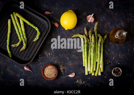 Frischer Spargel und Zutaten zum Kochen auf dunklem Hintergrund. Flach. Ansicht von oben Stockfoto