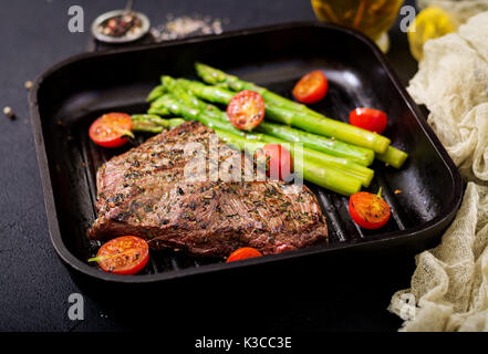 Saftiges steak selten Rindfleisch mit Gewürzen auf einem Holzbrett und Garnieren von Spargel. Stockfoto