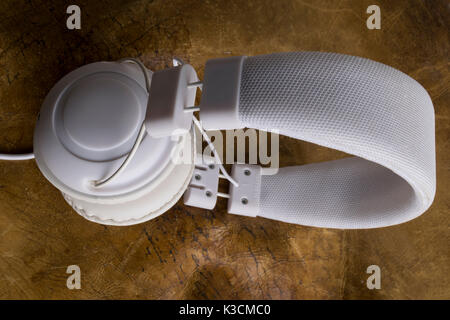 Isolierte moderne weiße Kopfhörer über einen Vintage Leder Hintergrund. Stockfoto