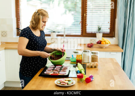 Schöne schwangere Frau Vorbereitung Muffins Stockfoto