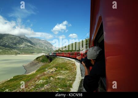 Berühmte rote alpine Zug Bernina Express von St. Moritz nach Tirano, vorbei an den Blanc See am Bernina Pass in der Schweiz Stockfoto