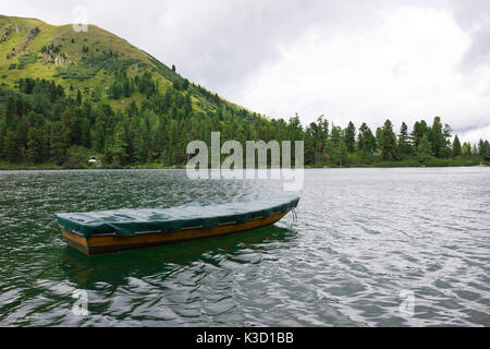 Ruderboot auf einem wunderschönen einsamen Bergsee mit frischen kristallklaren Wasser, umgeben von Wald. Malerische Landschaft in Österreich. Stockfoto