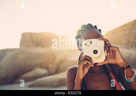 Afrikanische amerikanische Frauen fotografieren am Strand. Junge Frau mit der Kamera an einem sonnigen Tag. Stockfoto