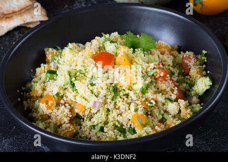 Libanesische arabische Küche: Gesunde leckere Salat mit Cous Cous, frisches Gemüse und grünen tabbouleh in schwarz Schüssel. Authentische Speisen Schüssel Stockfoto