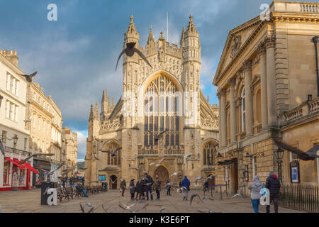 Bath UK Abbey, Blick auf das Westende von Bath Abbey im Zentrum der Stadt mit dem Pumpenraum und dem Eingang zu den römischen Bädern auf der rechten Seite, England. Stockfoto