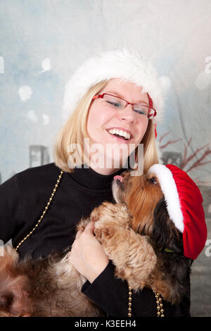 Junge Frau mit neuen Welpen in Santa Hüte Stockfoto