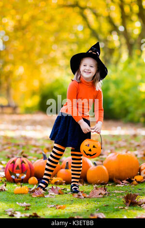 Kinder mit Kürbis an Halloween. Kleines Mädchen in Hexe Kostüm und Hut spielen im Herbst Park. Kind an Halloween Trick oder Festlichkeit. Kid Süßes oder Saures. Stockfoto