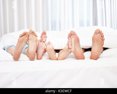 Nahaufnahme des Fußes einer Familie mit zwei Kindern im Bett Spaß haben. Stockfoto