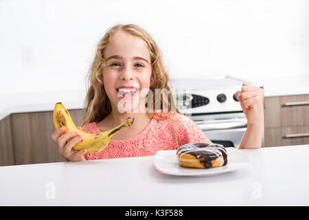 Kind die Wahl zwischen gesundes Gemüse und leckere Süßigkeiten Stockfoto