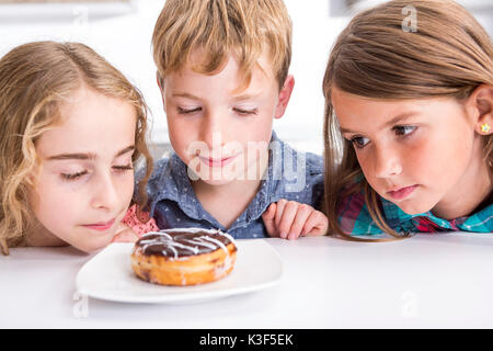 Junge Kind am Tisch sitzen Donut Stockfoto