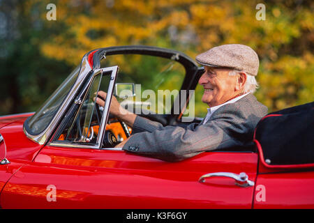 Senior sitzt in Red Old-timer Jaguar Cabrio Stockfoto