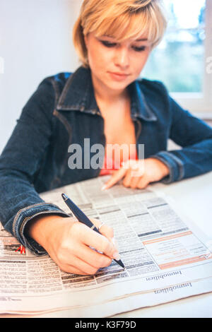 Junge, blonde Frau liest Zeitung angibt Stockfoto