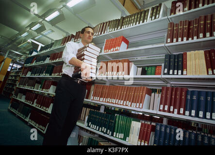 Der Mensch trägt Buch los in einer Bibliothek Stockfoto