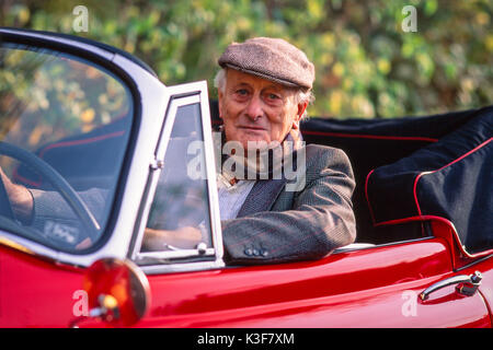 Senior sitzt in seinem rot-Oldtimer Jaguar Cabrio Stockfoto