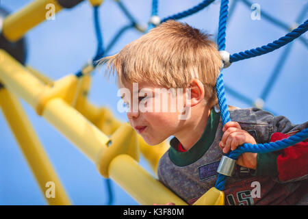 Kleiner Junge am Klettergerüst auf dem Spielplatz Stockfoto