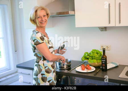 Lachend blonde Frau beim Kochen Stockfoto