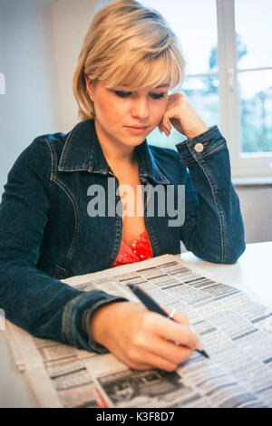 Junge, blonde Frau liest Zeitung angibt Stockfoto