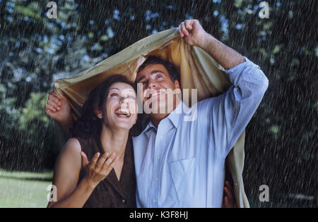 Paar schützt sich mit einer Jacke aus Regen Stockfoto