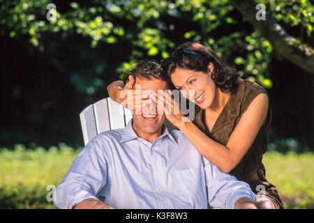 Lachend ein Paar im Garten, Frau, schließen Sie die Augen des Mannes Stockfoto