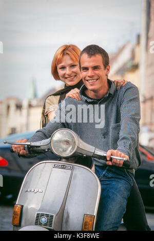 Junge Paare auf Vespa Motorroller Stockfoto