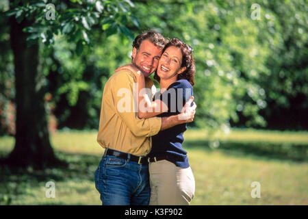 Lachend ein paar Umarmungen im Garten Stockfoto