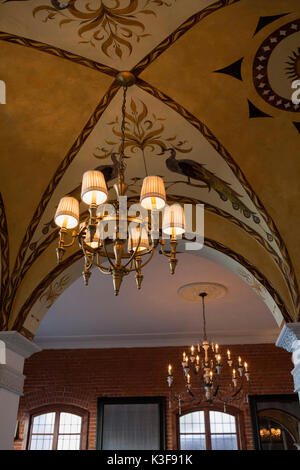 Niedrige Winkelansicht von zwei Kronleuchtern, die an der verzierten Decke hängen Stockfoto