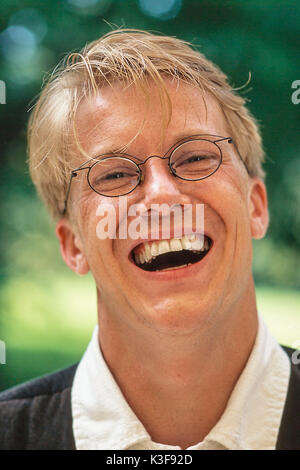 Lachend blonder Mann mit Brille Stockfoto