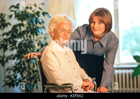 Junge Frau im Gespräch ein Senior in der Nähe, der sitzt im Rollstuhl Stockfoto