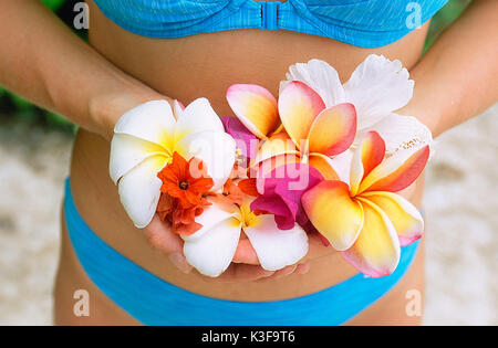 Frau im Bikini hält Plumeria Stockfoto