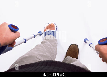 Mann geht mit Bein in Gips in Krücken Stockfoto