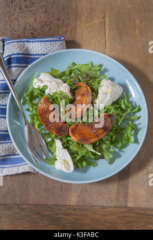 Grüner Salat, gebratene Pfirsiche, Burrata auf blauen Platte Stockfoto