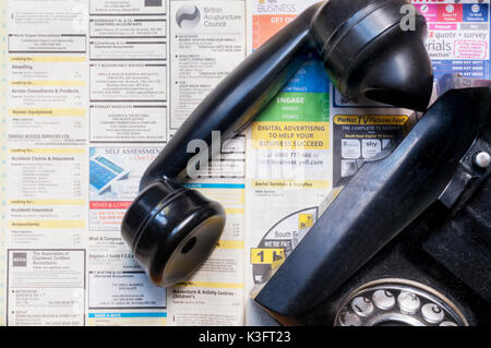 Einen alten Telefonhörer auf eine Kopie von Gelbe Seiten, die Veröffentlichung in gedruckter Form im Jahr 2018 zu stoppen ruhen Stockfoto