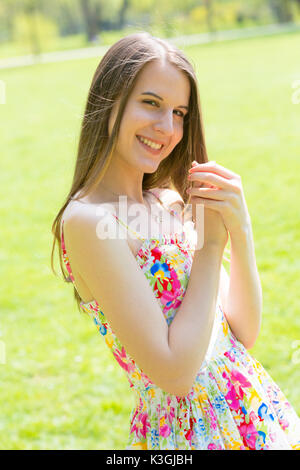 Porträt der jungen schönen Frau mit langem Haar zu tragen Blumen Kleid in grün Spring Park Stockfoto