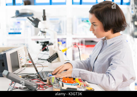 Weibliche Laboratory Assistant Reparaturen PCB-Modul für CNC Robotik. Messung der Parameter der elektronischen System im Labor Stockfoto