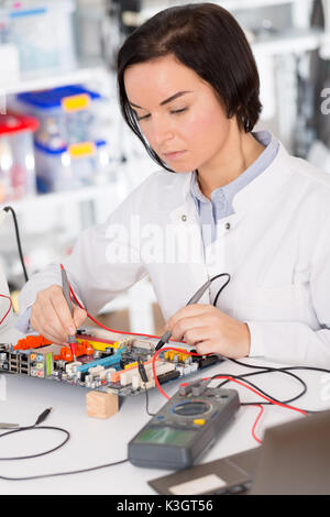 Weibliche Laboratory Assistant Reparaturen PCB-Modul für CNC Robotik. Messung der Parameter der elektronischen System im Labor Stockfoto