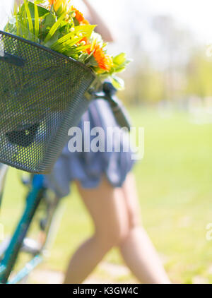 Mädchen in einem Kleid steht neben einem Fahrrad, auf einen Blumenstrauß Fokus Stockfoto